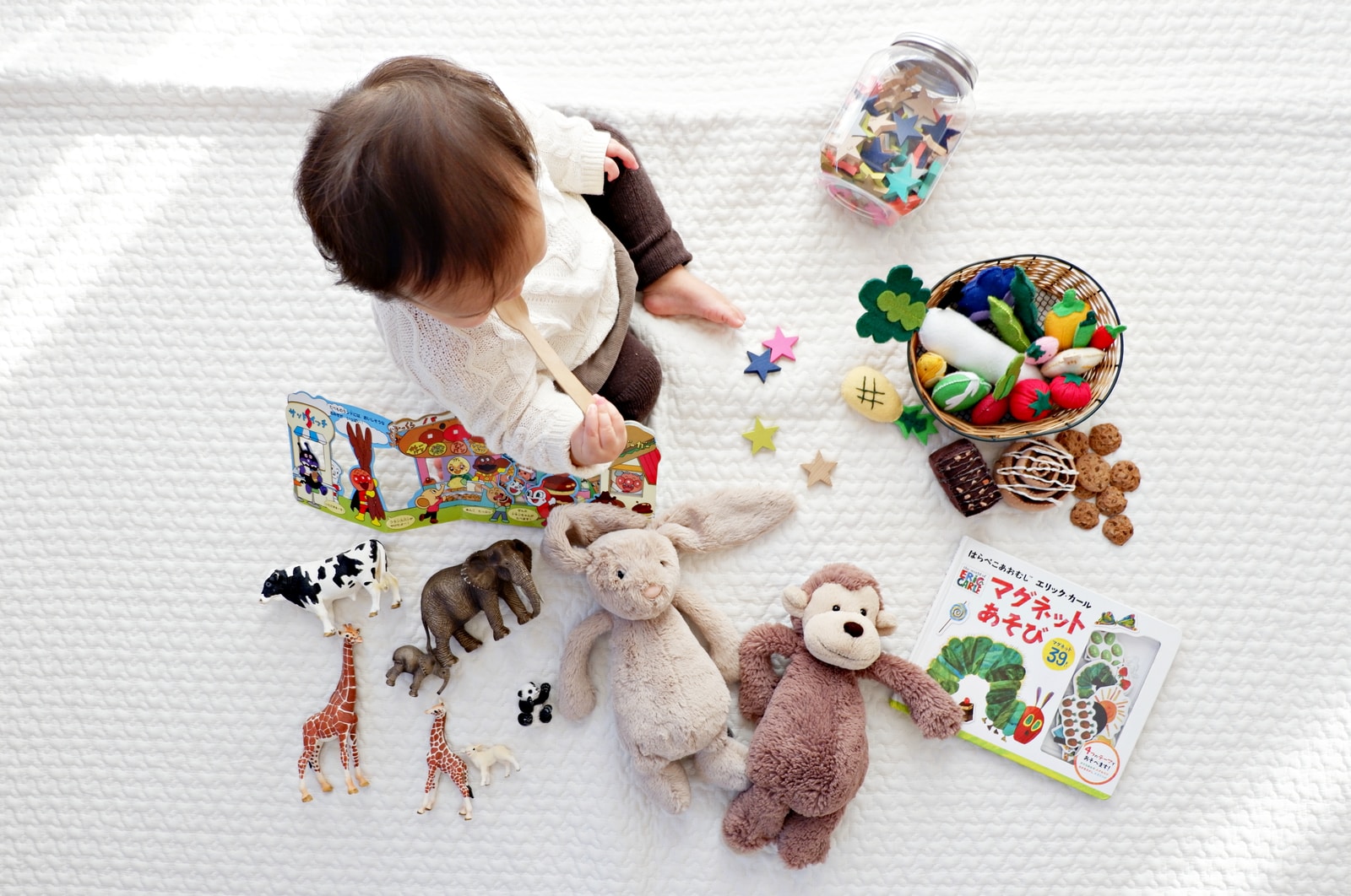 Photo par Shirota Yuri boy sitting on white cloth surrounded by toys
